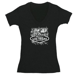 May include: Black V-neck t-shirt with a white graphic of the Las Vegas sign and the text "Welcome to Fabulous Las Vegas Nevada".