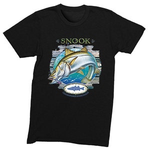 May include: Black t-shirt with a graphic of a snook fish jumping out of the water. The fish is surrounded by a blue circle and a wooden plank background. The text "Snook" is above the fish and "Centropomus undecimalis" is below the fish.