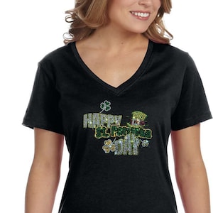 以下が含まれることがあります： 緑の帽子をかぶった妖精が描かれた、"Happy St. Patrick's Day"と輝くラインストーンで飾られた黒いVネックTシャツです。