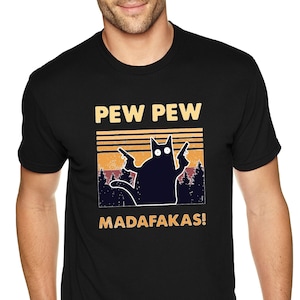 May include: Black t-shirt with a retro-style graphic of a cat holding two guns. The text "PEW PEW MADAFAKAS!" is printed on the shirt.