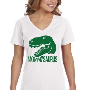 May include: White V-neck t-shirt with a green dinosaur head graphic and the text "MOMMYSAURUS" printed on the front.