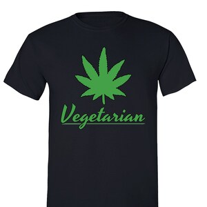 Puede incluir: Una camiseta azul oscuro con una hoja de marihuana verde y el texto "Vegetarian" en verde.