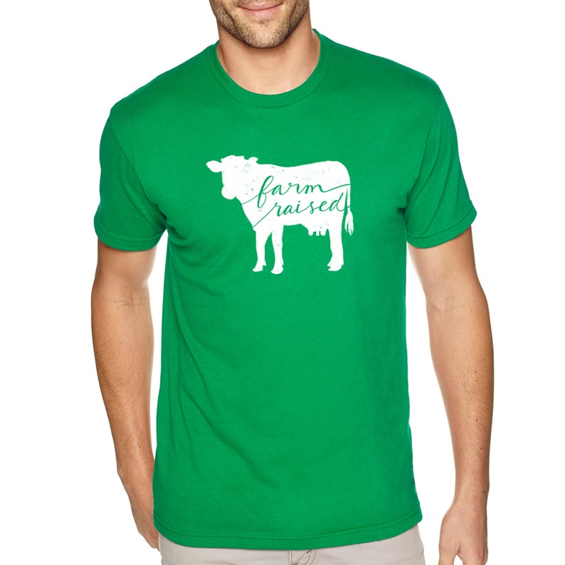 May include: A green t-shirt featuring a white silhouette of a cow and the text "farm raised" in cursive.