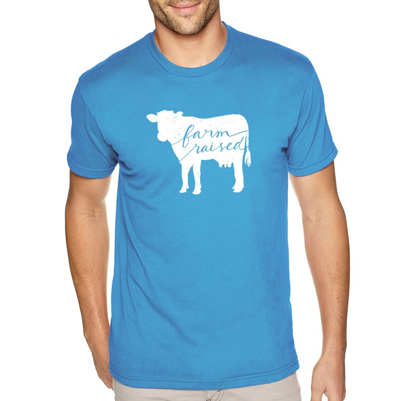 May include: A bright blue t-shirt with a white silhouette of a cow and the text "farm raised" printed on the front.