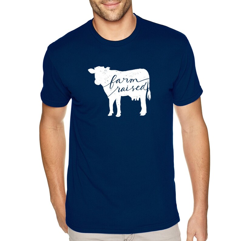 May include: A navy blue t-shirt with a white silhouette of a cow and the text "farm raised" printed on the front.