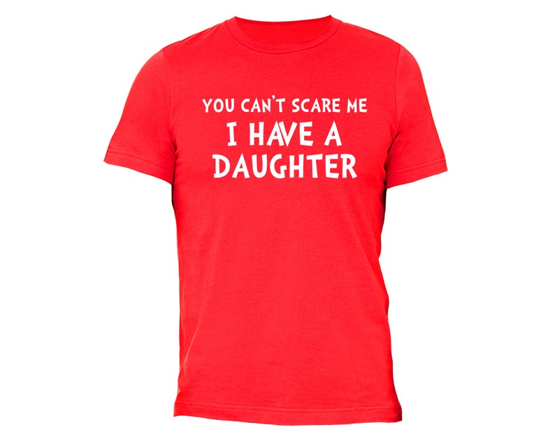 Puede incluir: Una camiseta roja con el texto blanco "YOU CAN'T SCARE ME I HAVE A DAUGHTER". La camiseta es de cuello redondo y parece estar hecha de un material suave.