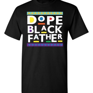 May include: Black t-shirt with the words "DOPE BLACK FATHER" in a colorful, geometric design. The text is in white, with the letters "D" and "A" in yellow and red, respectively. The shirt has a crew neck and short sleeves.