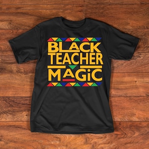 May include: Black t-shirt with the text "Black Teacher Magic" in yellow letters with a colorful geometric pattern below the text.