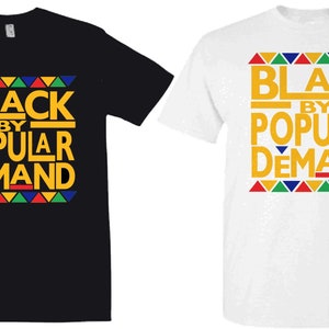 May include: Two t-shirts with the text "Black by Popular Demand" in yellow letters on a black and white background. The text is surrounded by a colorful geometric pattern.