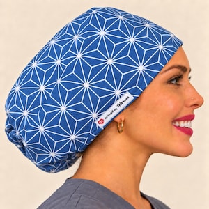 May include: A blue scrub cap featuring a white geometric star pattern. The fabric head covering has a white rectangular tag on the side with the text "everyday Heroes" in black lettering and a small red logo icon next to the brand name.