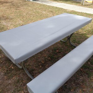 Puede incluir: Una cubierta de mesa de picnic gris con una cubierta de banco a juego. La cubierta est&aacute; hecha de un material impermeable y est&aacute; dise&ntilde;ada para proteger la mesa de los elementos.