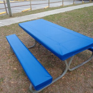 May include: A blue picnic table cover with a matching bench cover. The cover is made of a waterproof material and is designed to protect the table from the elements.