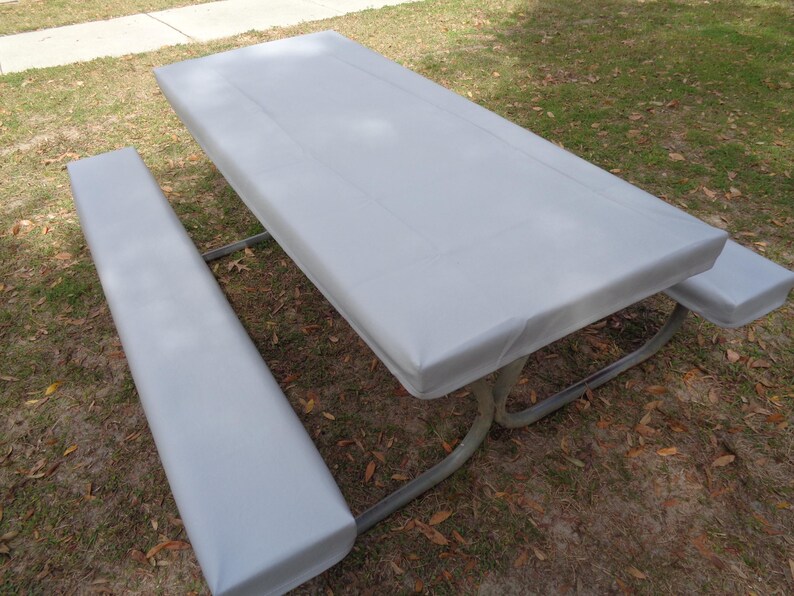 Puede incluir: Una cubierta de mesa de picnic gris con una cubierta de banco a juego. La cubierta est&aacute; hecha de un material impermeable y est&aacute; dise&ntilde;ada para proteger la mesa de los elementos.