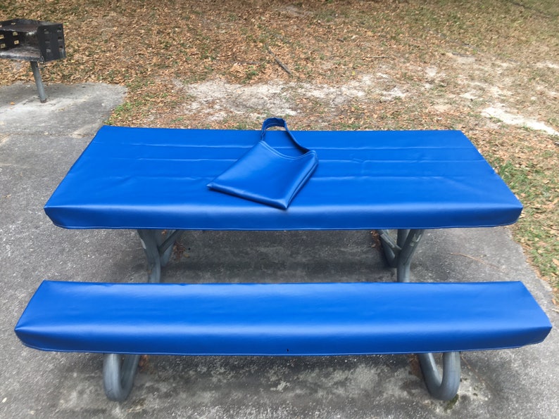May include: Blue picnic table cover with a matching bench cover. The cover is made of a waterproof material and is designed to protect the table from the elements.