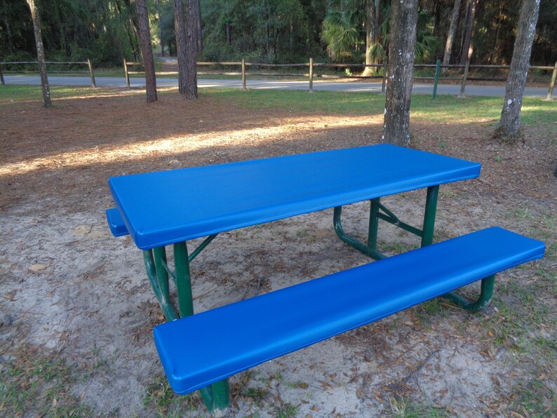 May include: A blue picnic table with a matching blue bench. The table and bench are made of metal with a green frame.