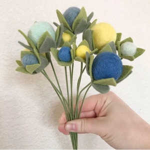 May include: A bouquet of felt flowers with green leaves and blue, yellow, and light green felt balls.