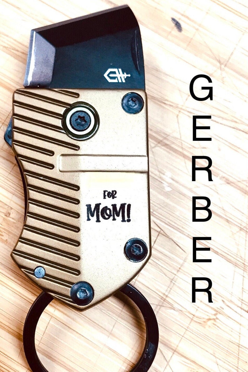 May include: A gold and black pocket knife with a ring on the handle. The knife has a Gerber logo and the words "For Mom!" engraved on the side.