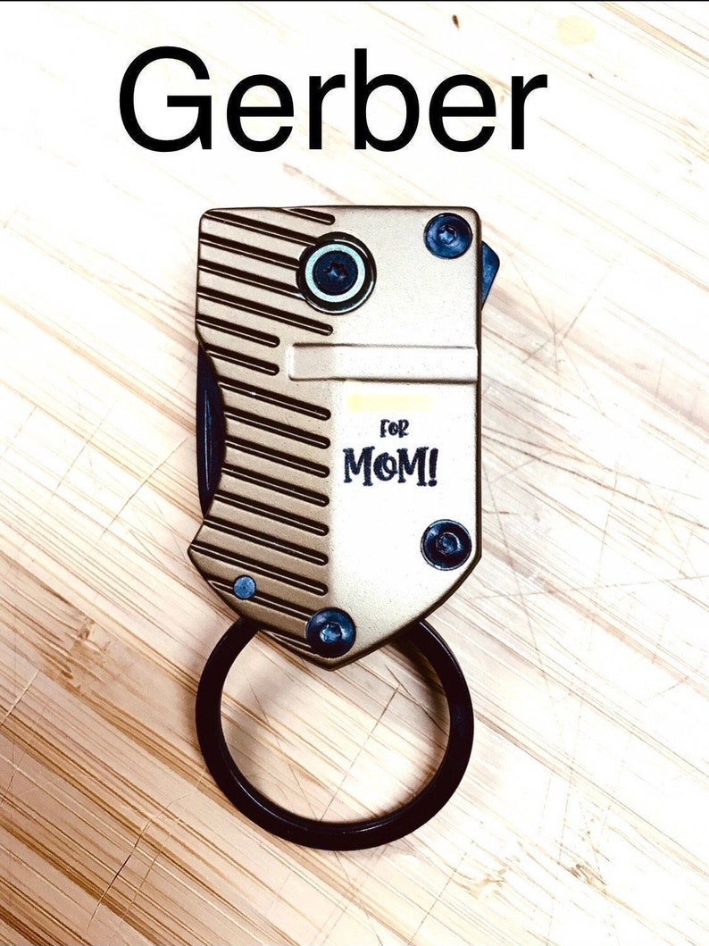 May include: A gold-coloured Gerber multi-tool with a black ring and the words "for MOM!" on the front.