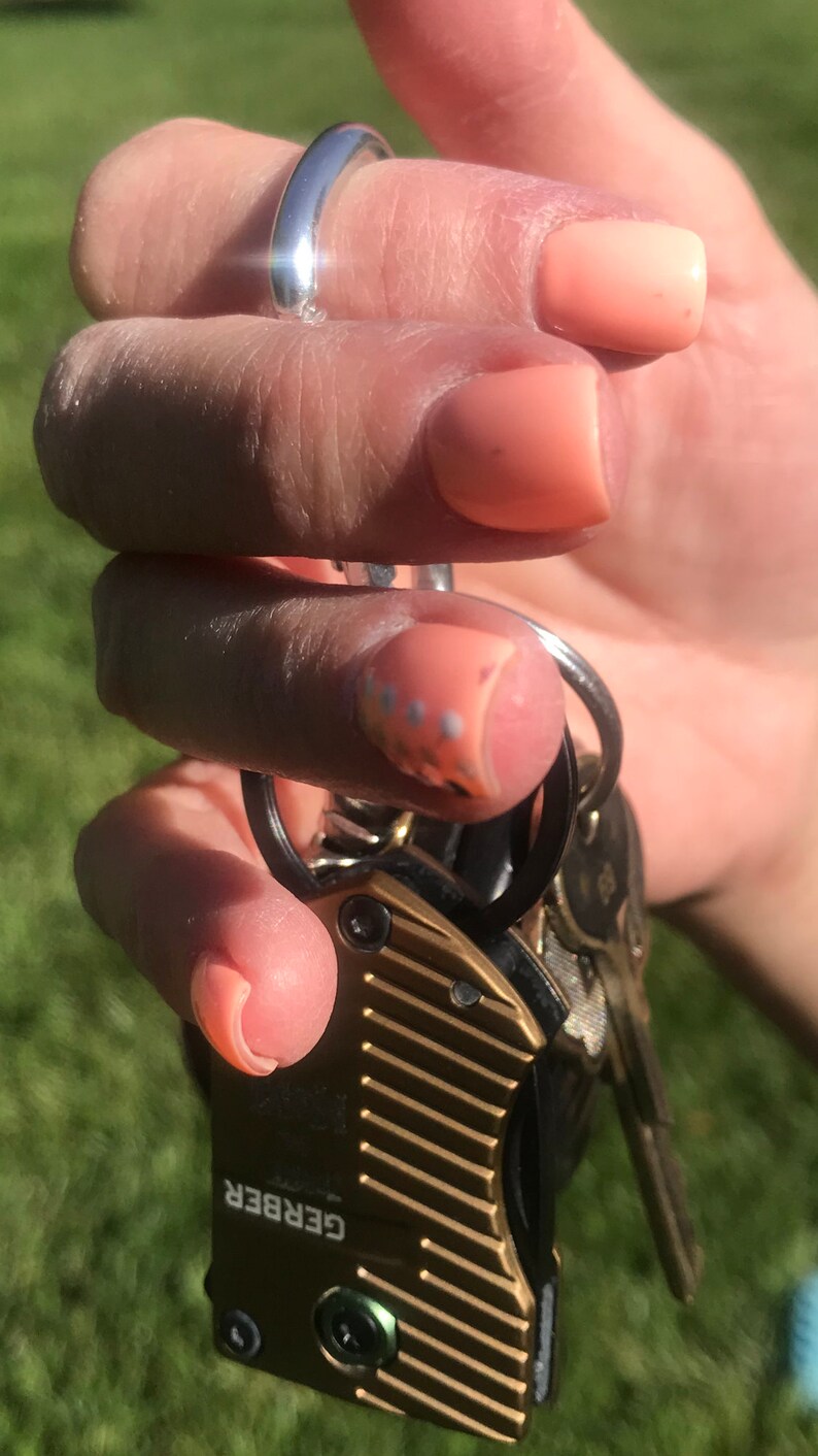 May include: A gold Gerber multi-tool with a black handle and a silver keyring. The multi-tool has a textured surface and the word "GERBER" is printed on the side.