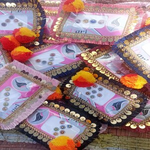 Op de afbeelding: Een stapel kleine, decoratieve, ingelijste kaarten met kleurrijke strass steentjes en pailletten. De kaarten zijn roze, zwart en blauw met gouden randjes. Elke kaart heeft een kleine, witte sticker met een ontwerp van een vrouwen gezicht en een paar strass steentjes. De kaarten zijn versierd met kleine, kleurrijke pompoentjes.