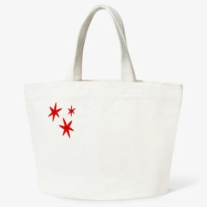 Peut inclure: Sac fourre-tout en toile blanc cassé avec trois étoiles rouges. Le sac a une forme rectangulaire et une paire de poignées en toile assorties.