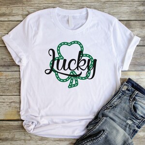 May include: White t-shirt with a green shamrock design and the word "lucky" in black script.