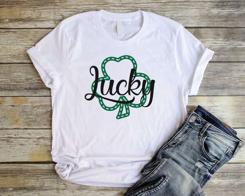 May include: White t-shirt with a green shamrock design and the word "lucky" in black script.