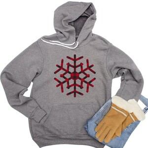 May include: A gray hoodie with a red and black plaid snowflake design. The hoodie has a drawstring hood and a kangaroo pocket.