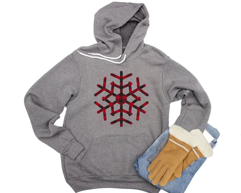 May include: A gray hoodie with a red and black plaid snowflake design. The hoodie has a drawstring hood and a kangaroo pocket.