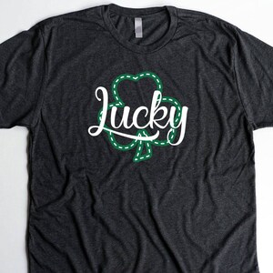 May include: A dark gray t-shirt with a green shamrock and the word "lucky" in white lettering.