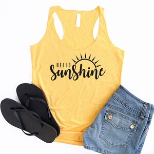 May include: Yellow tank top with a black graphic that says "Hello Sunshine" with a sun graphic above the text.