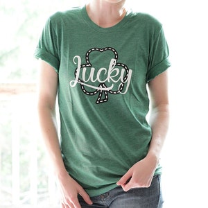 May include: A green t-shirt with a white shamrock and the word "lucky" in a white cursive font.