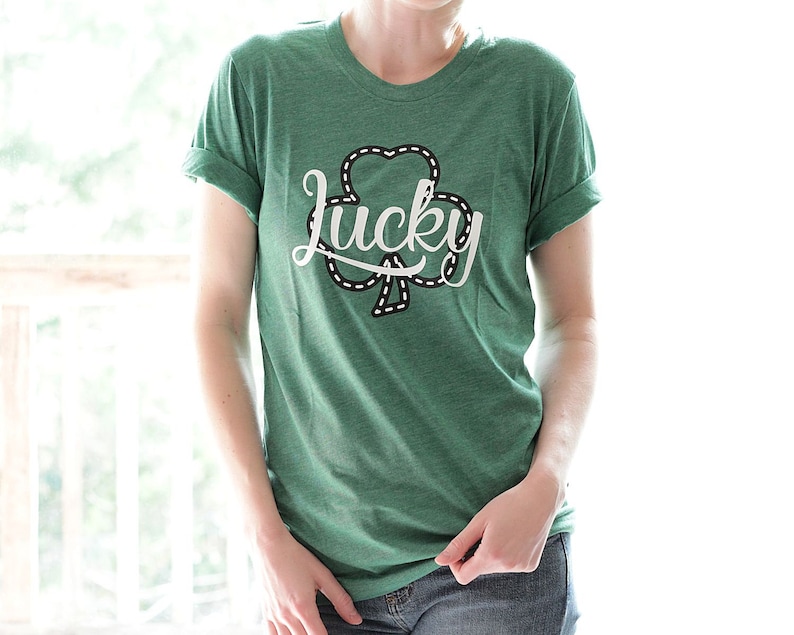 May include: A green t-shirt with a white shamrock and the word "lucky" in a white cursive font.
