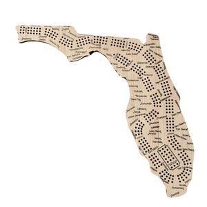 May include: A wooden game board shaped like the state of Florida with the names of cities and towns throughout the state. The board has a light brown color and is made of wood. The board is designed for a game of trivia or a game of chance.