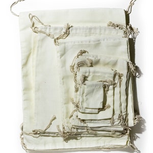 May include: A set of 10 off-white cotton drawstring bags of various sizes, nested inside each other. The bags are made of natural fabric and have a rustic, handmade look.