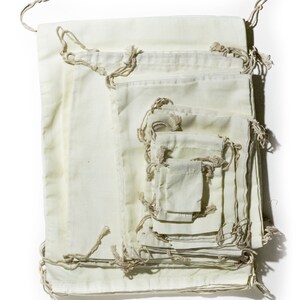 May include: A set of 10 off-white cotton drawstring bags of various sizes, nested inside each other. The bags are made of natural fabric and have a rustic, handmade look.