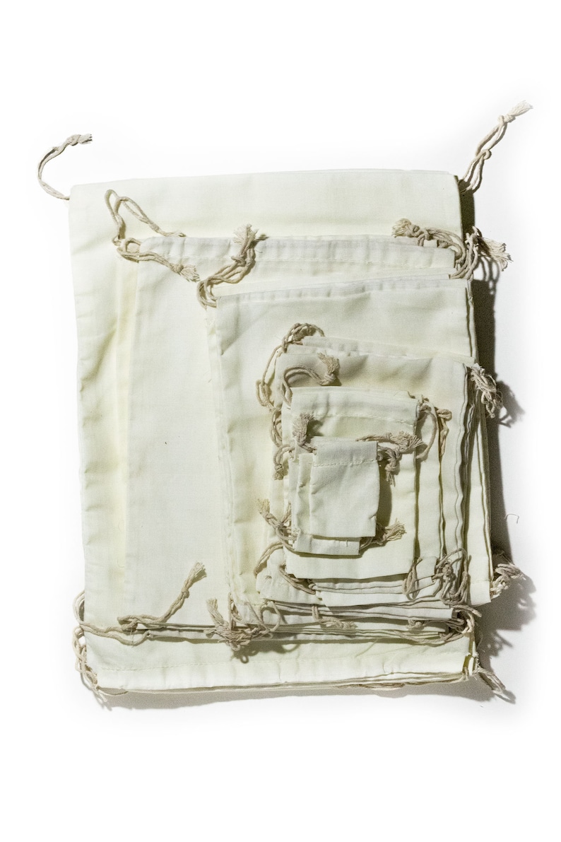 May include: A set of 10 off-white cotton drawstring bags of various sizes, nested inside each other. The bags are made of natural fabric and have a rustic, handmade look.