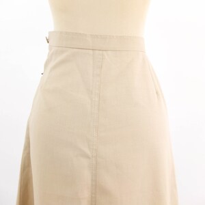 May include: A beige skirt with a straight cut and a simple design. The skirt is made of a lightweight fabric and has a zip closure at the back.