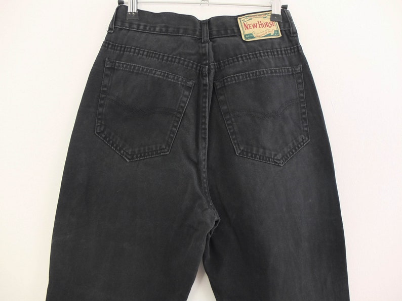 May include: Black denim jeans with a back pocket and a small rectangular label that says "New Horse" in white text.