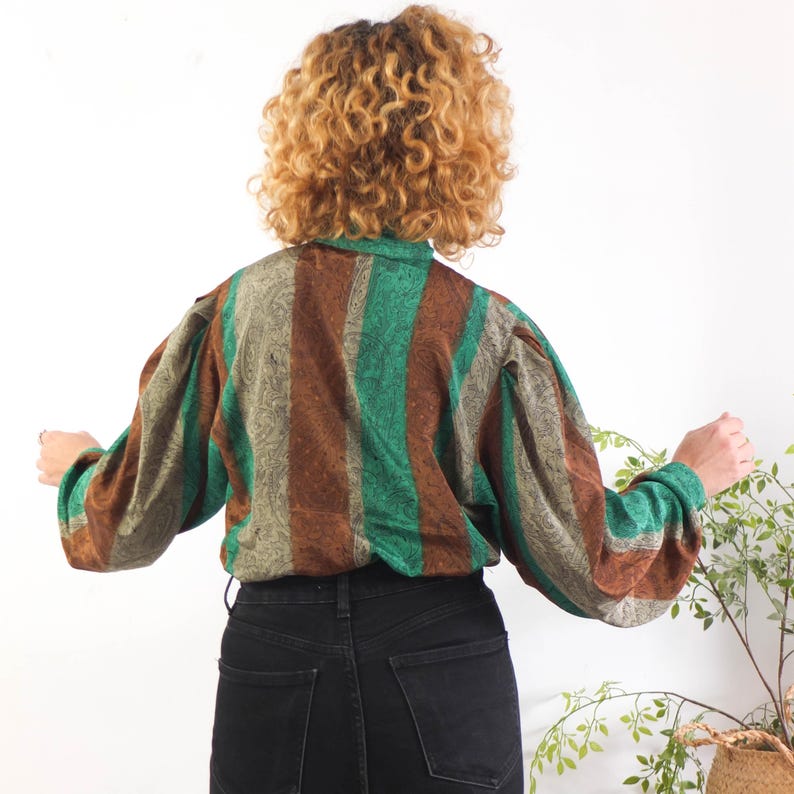 The 80s New Wave button down blouse is polyester fabric in excellent vintage condition.