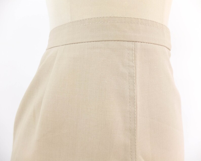 May include: A beige skirt with a straight cut and a seam down the centre back.