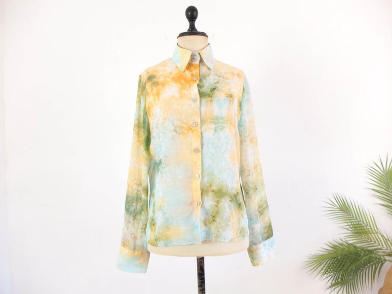 Op de afbeelding: Een overhemd met lange mouwen en een aquarelpatroon in geel, groen en blauw. Het overhemd heeft een kraag en manchetten en wordt gepresenteerd op een paspop tegen een witte achtergrond.