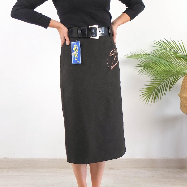 Vintage 80s black pencil skirt with midi length for party style women size Medium. This 1980s evening skirt has high waist with wide patent leather belt and glitter pattern.