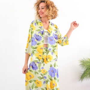 May include: A green, yellow, and purple floral print two-piece set with a collared jacket and a skirt.