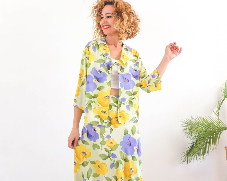 May include: A green, yellow, and purple floral print two-piece set with a collared jacket and a skirt.
