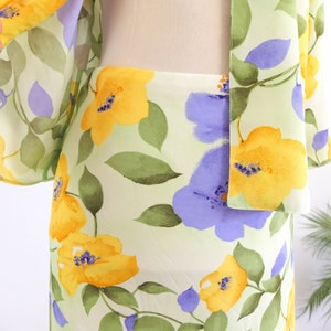 May include: A light green, yellow, and purple floral print skirt. The skirt is made of a lightweight fabric and has a flowy silhouette.