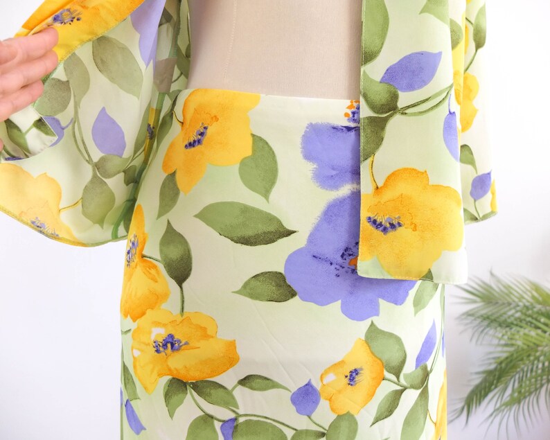 May include: A light green, yellow, and purple floral print skirt. The skirt is made of a lightweight fabric and has a flowy silhouette.