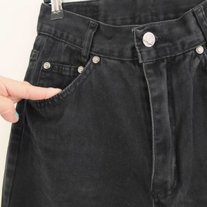 May include: Black denim pants with a front pocket and a button fly.