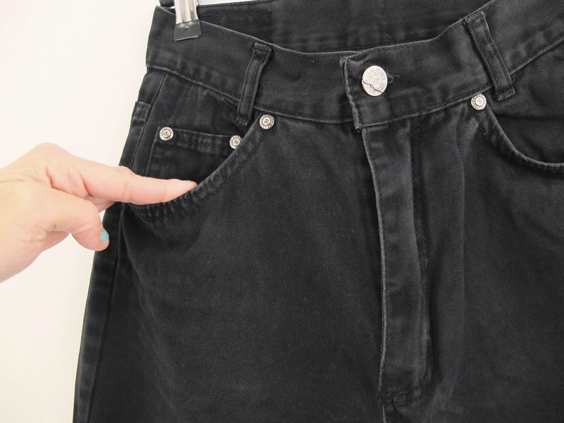 May include: Black denim pants with a front pocket and a button fly.