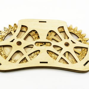 Peut inclure: Un puzzle en bois avec un design circulaire et le mot "VPL" au centre. Le puzzle comporte plusieurs engrenages avec des lettres et des chiffres dessus.